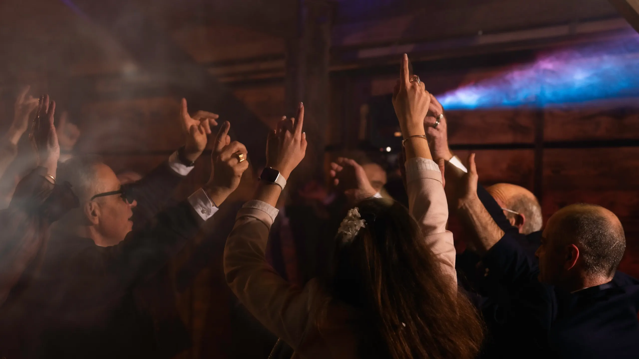 Invités festifs levant les bras sur la piste de danse lors d'une soirée d'anniversaire animée par le DJ Sonofactory en Bretagne, sous un éclairage professionnel.