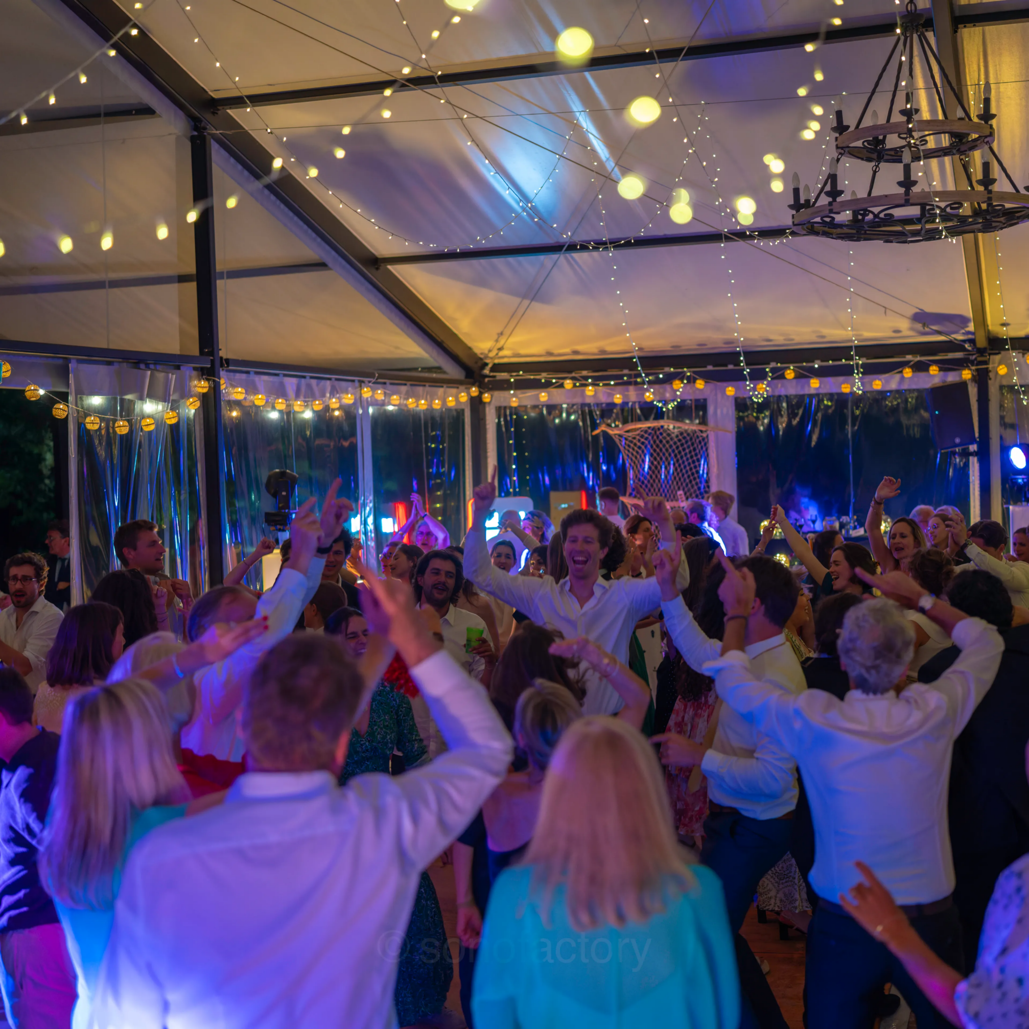 Invités dansant sur la piste sous un ciel de guirlandes lumineuses lors d'une soirée de mariage animée par le DJ Sonofactory près de Saint-Brieuc.